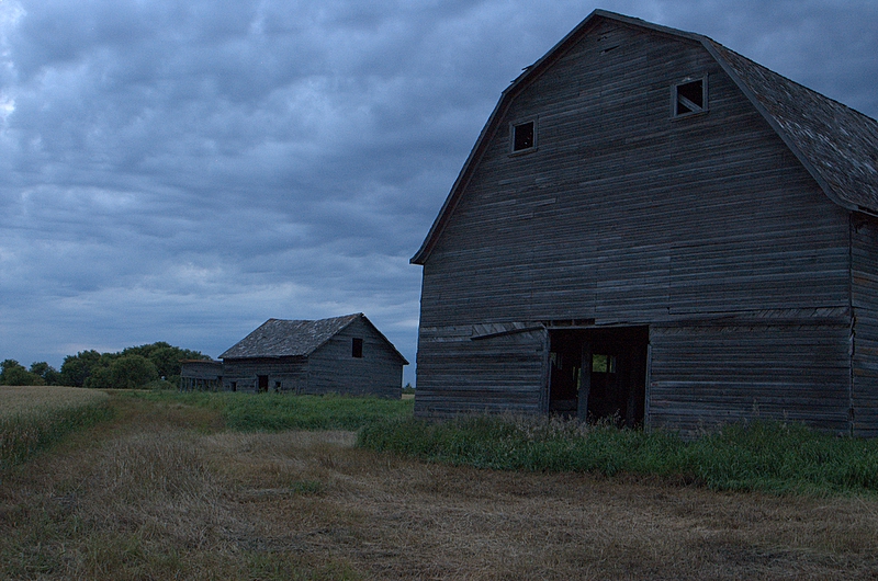 an old barn sitting in the middle of a field