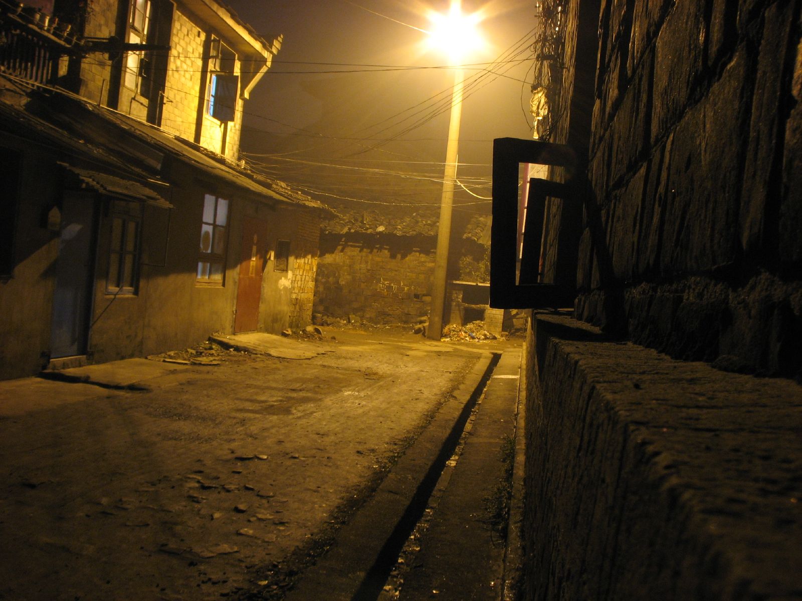 an alley that has a street lamp in the dark