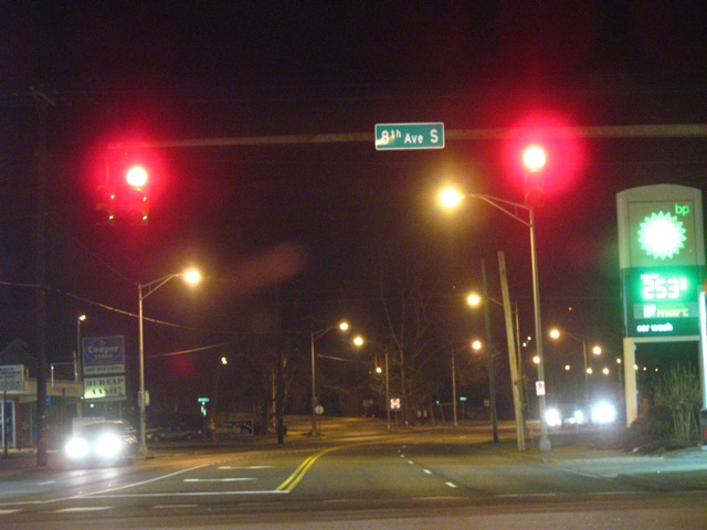street lights illuminate signs and traffic lights over an empty intersection