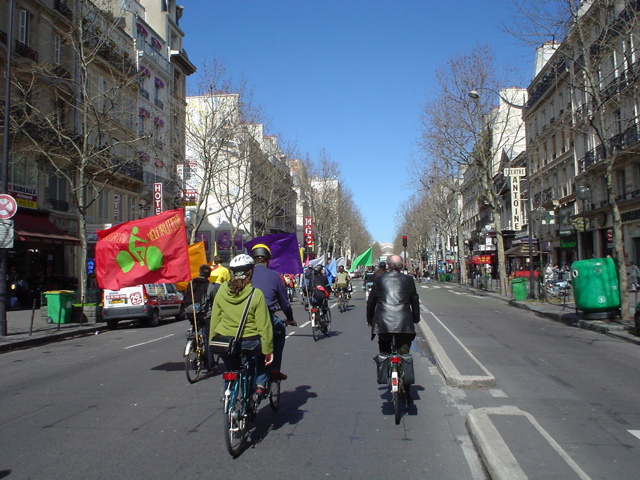 many people ride bicycles in the street and flagged vehicles are passing
