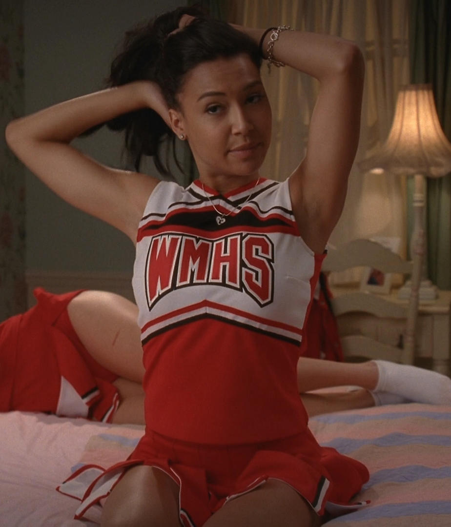 a girl in a cheerleader uniform on a bed