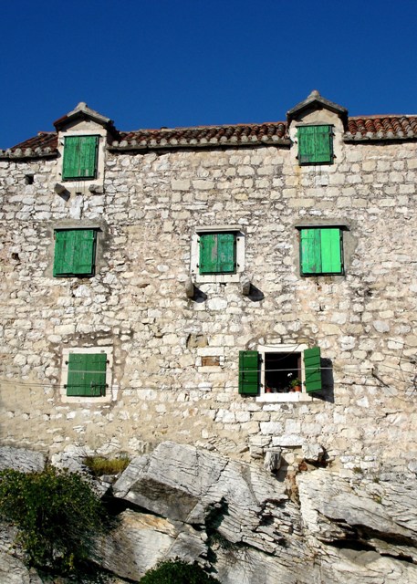 a building with windows and green shutters on the top