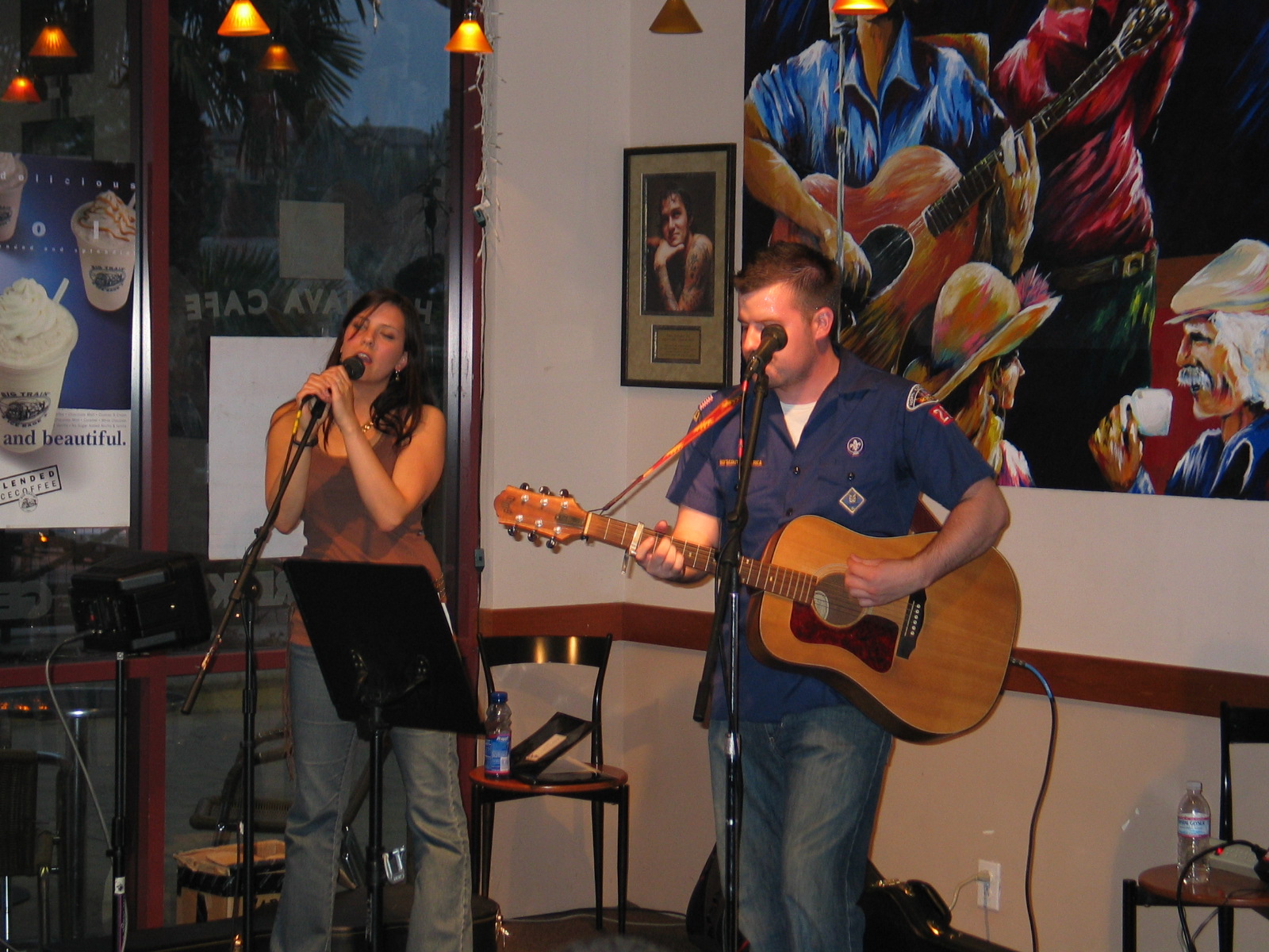 a man and woman playing guitars together in a bar