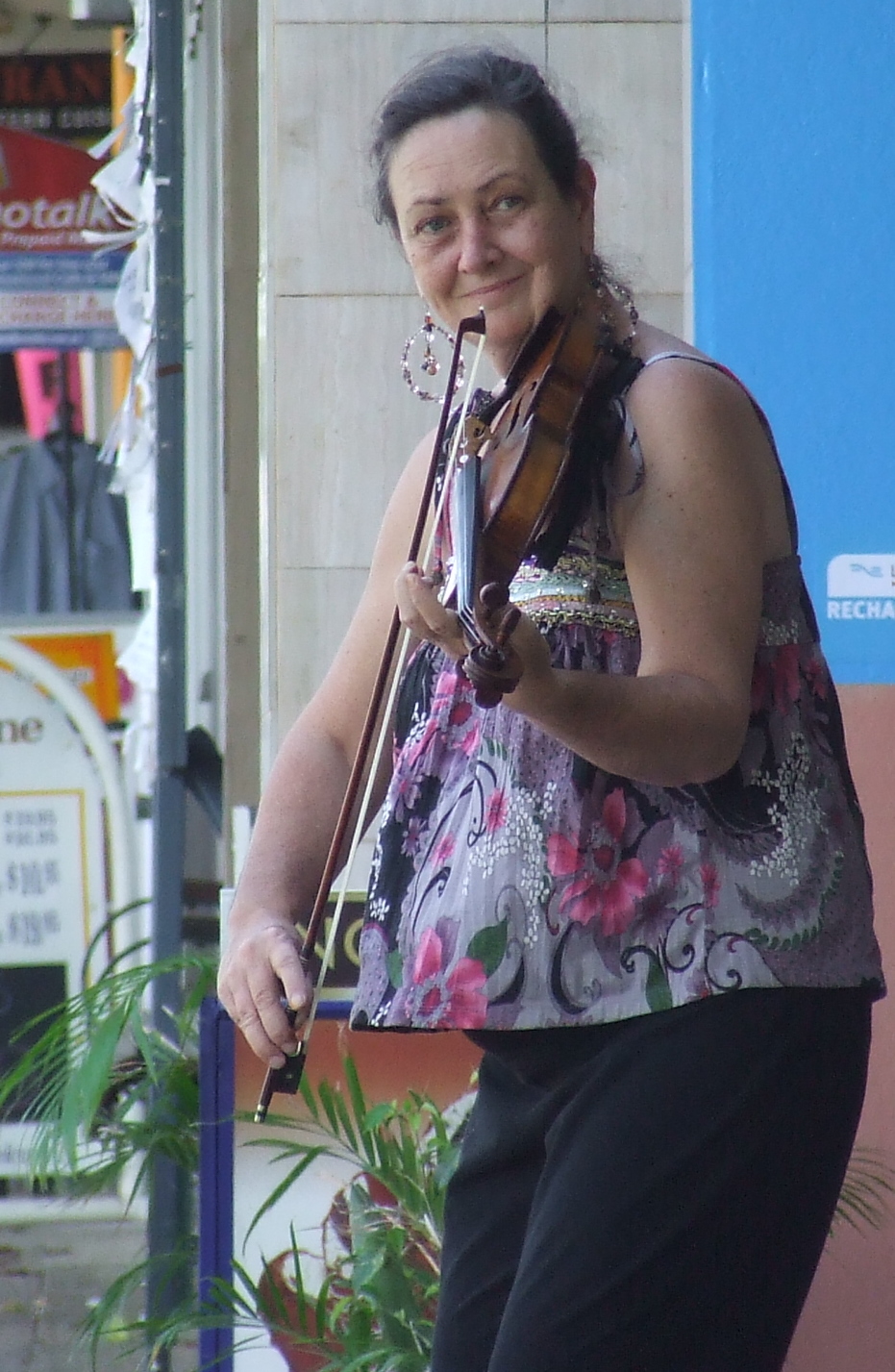 a woman playing violin on the street during the day