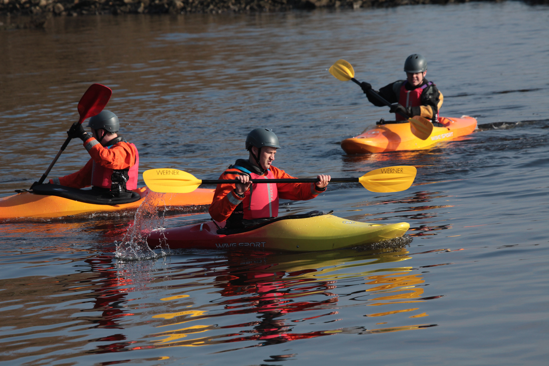 three people in kayaks on a river