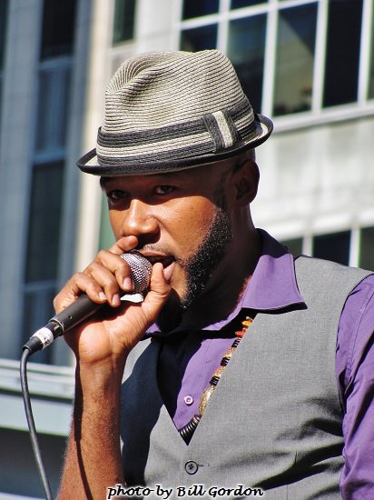 man in hat sings into microphone while outside