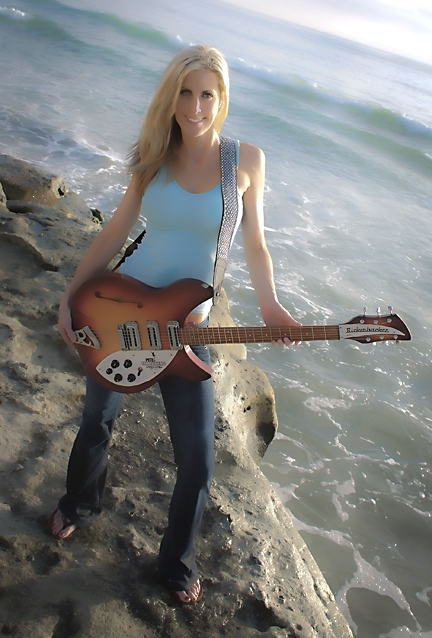 a woman in the sand is holding a guitar