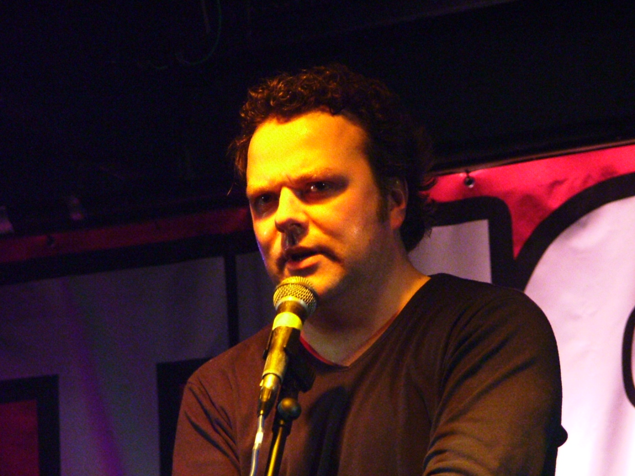 a man is holding a microphone and wearing a brown shirt