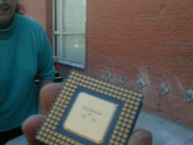 a man holds a piece of computer chip in front of his house