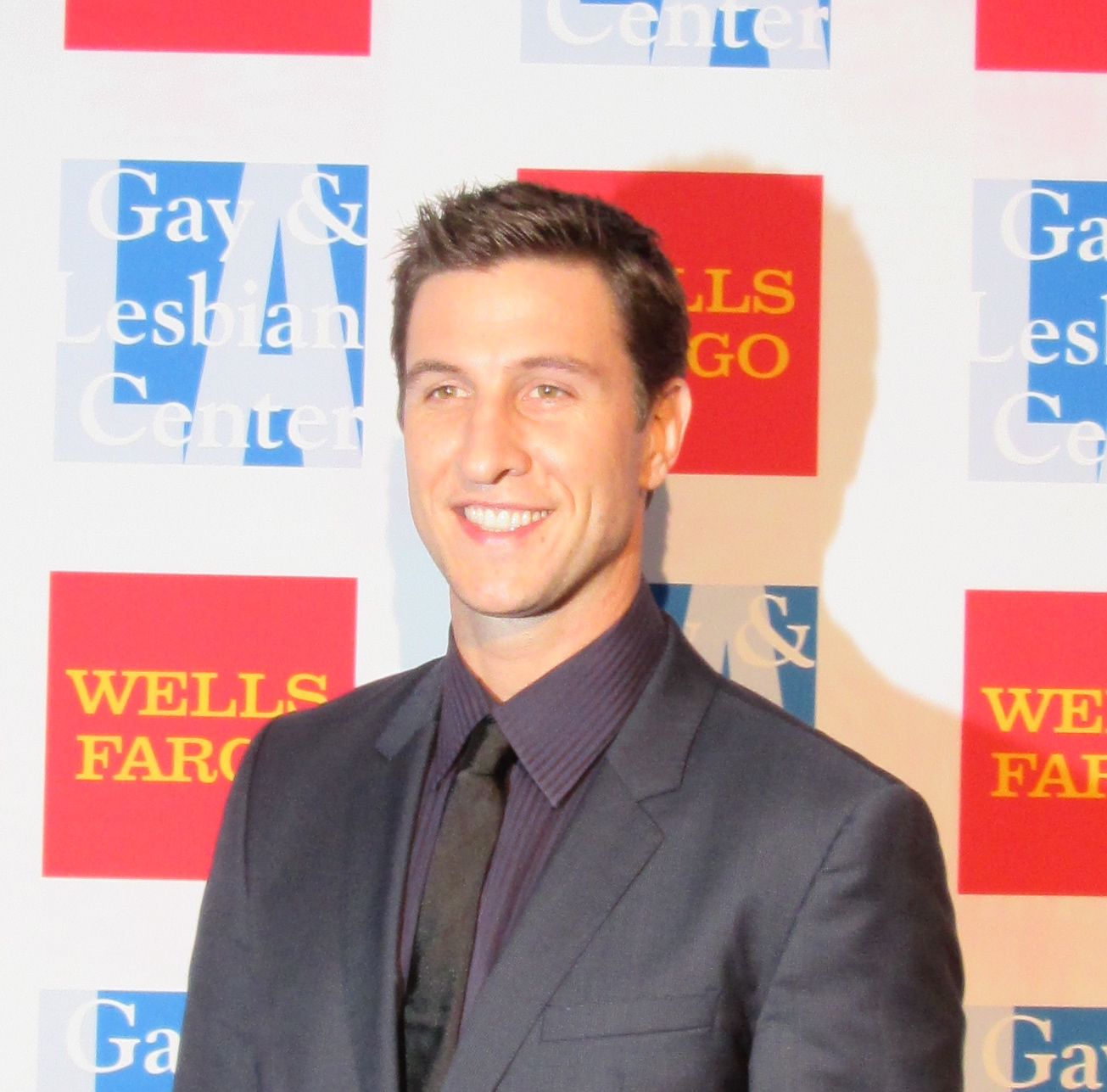 a man wearing a suit stands on a red and blue carpet