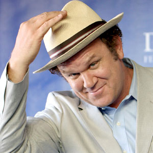 a man in a grey suit and hat looking into the camera