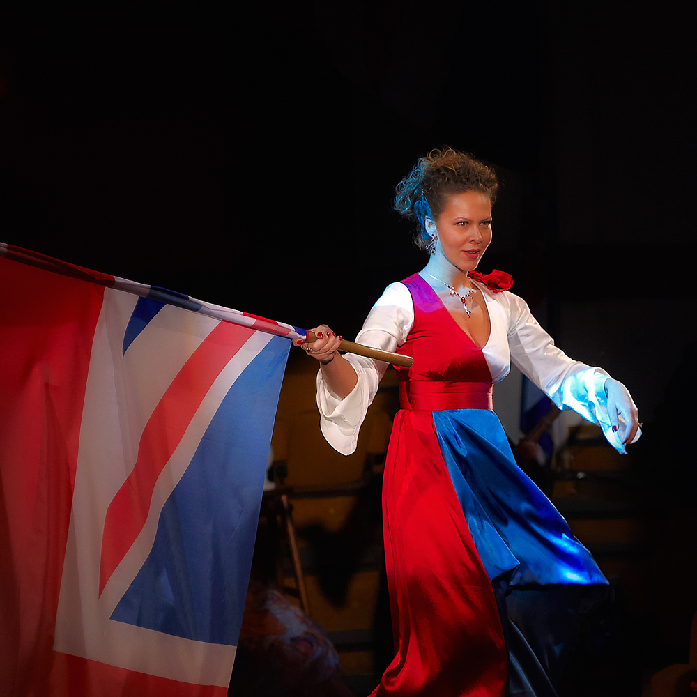 a woman wearing a red, white and blue dress is holding a flag