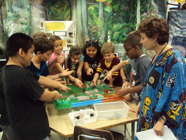 children in a science lab looking at an experiment table