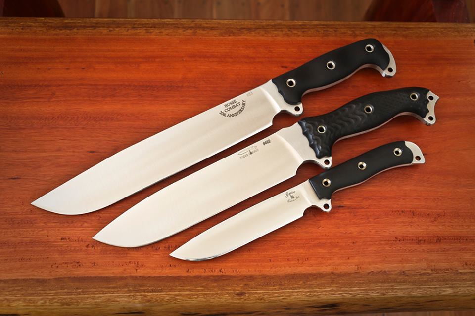 three knives with black handles are placed on a wooden table