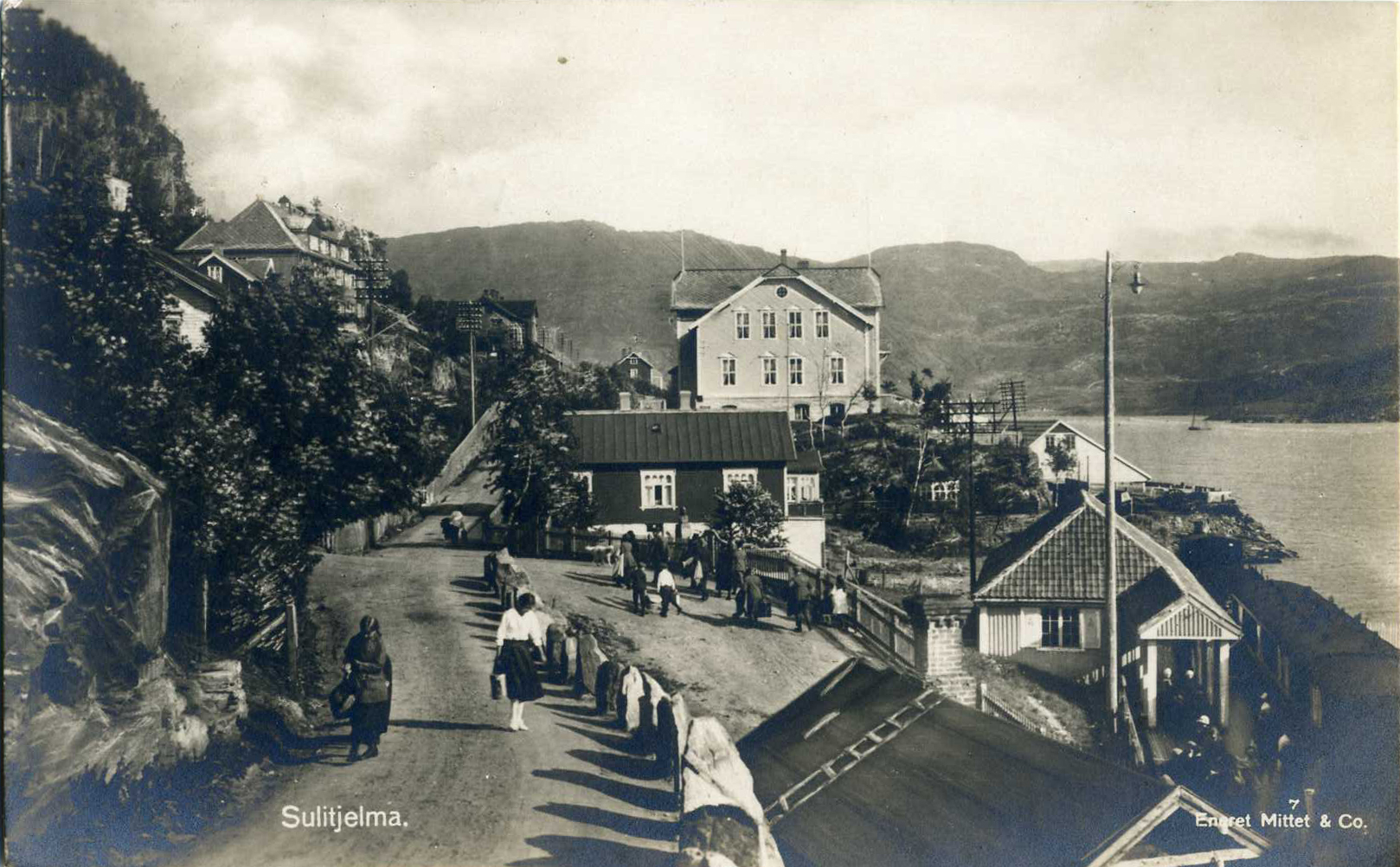 an old pograph of people walking down the road