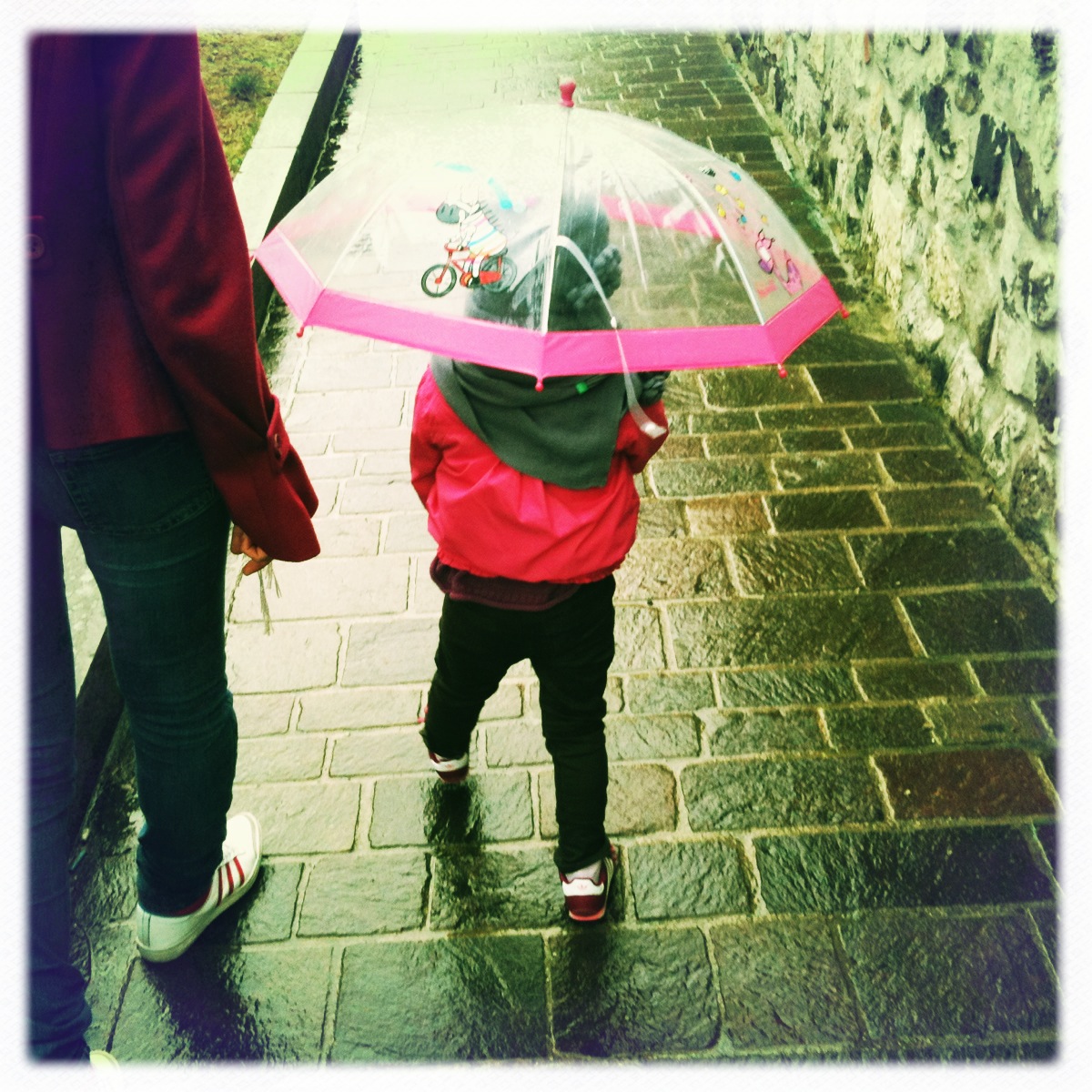 a child with an umbrella on the sidewalk