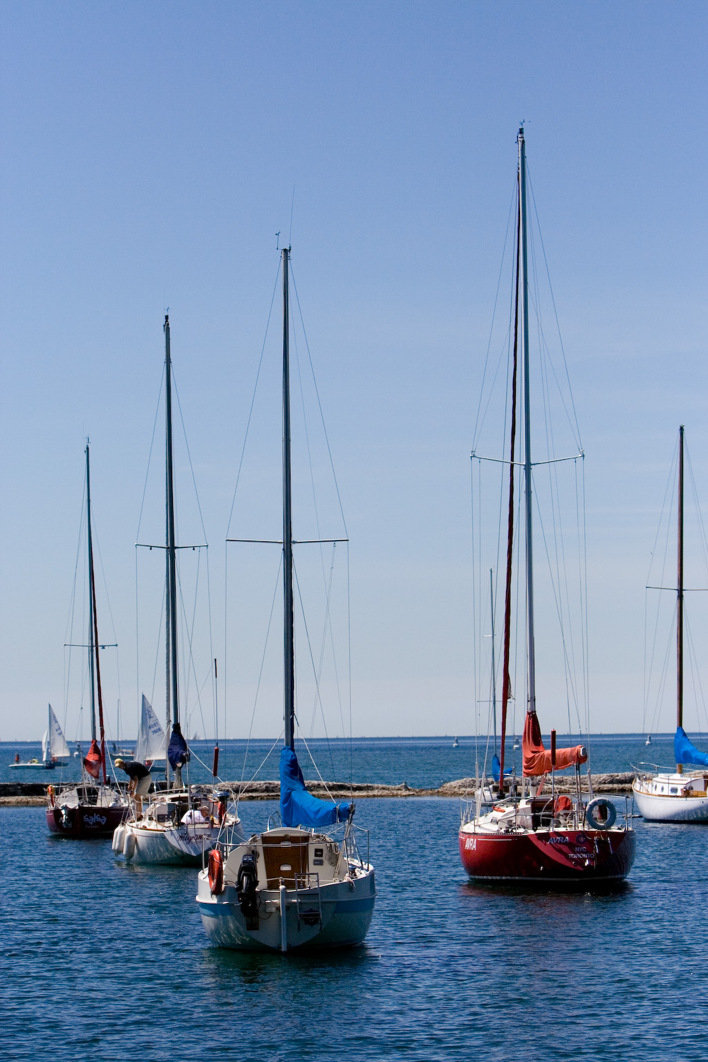 several sail boats in the blue ocean water