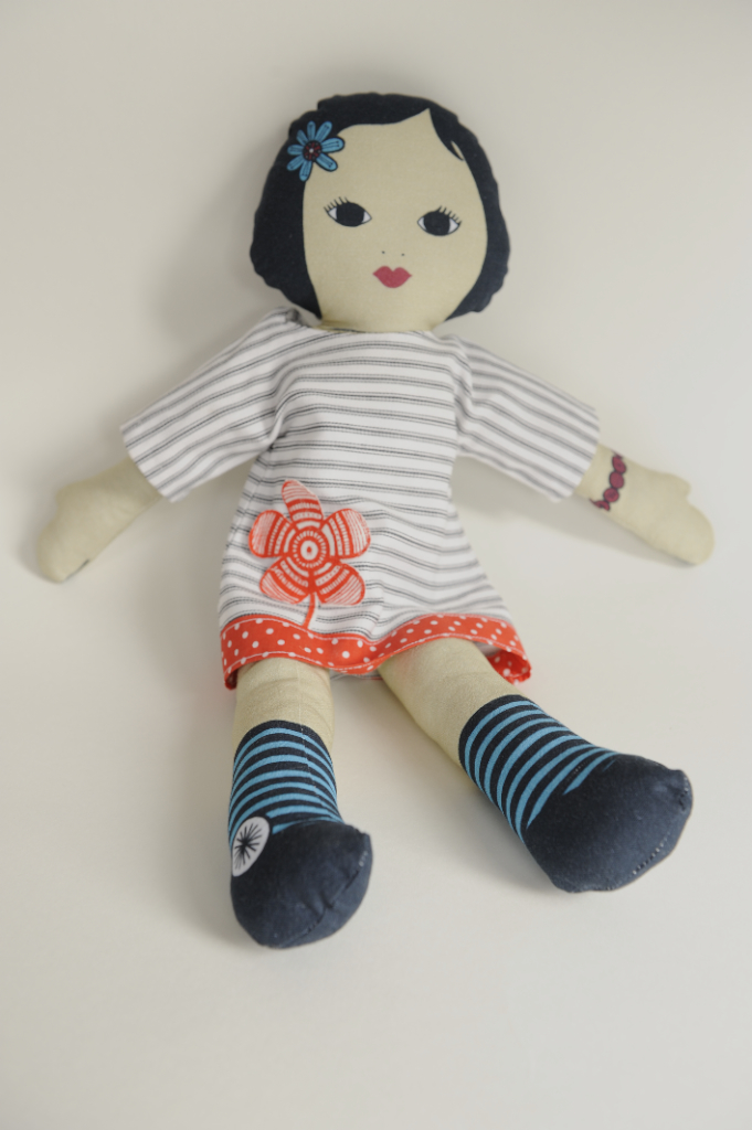an adorable stuffed doll is wearing a striped shirt and socks