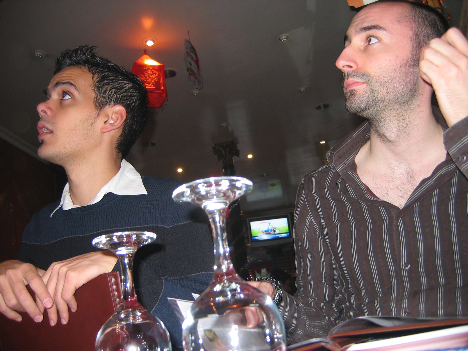two men seated at a bar one holding a candle