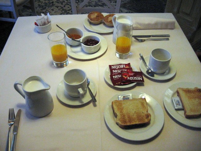 a table topped with plates and cups of breakfast food