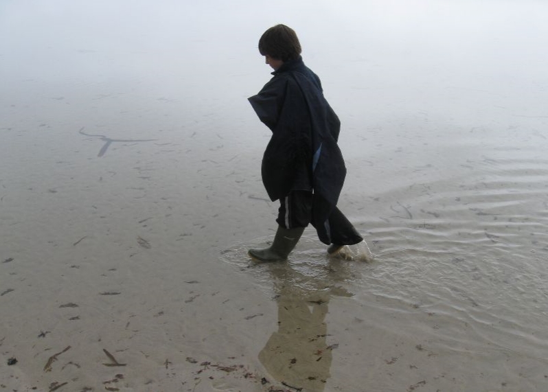a young person walking out of the water in rain