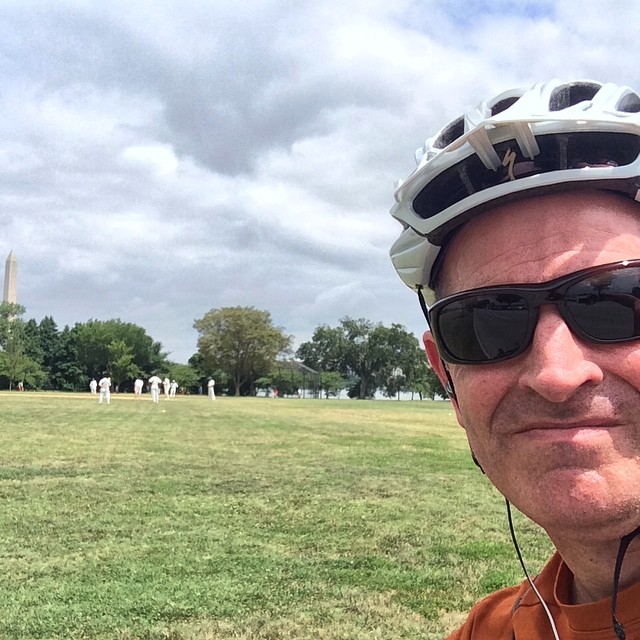 a man is in front of the washington monument wearing sunglasses and a bicycle helmet