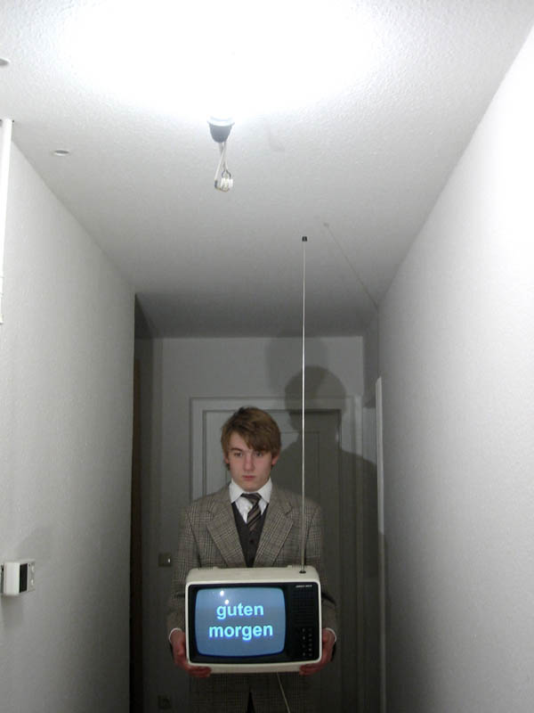 man holding an old vintage television in a hallway