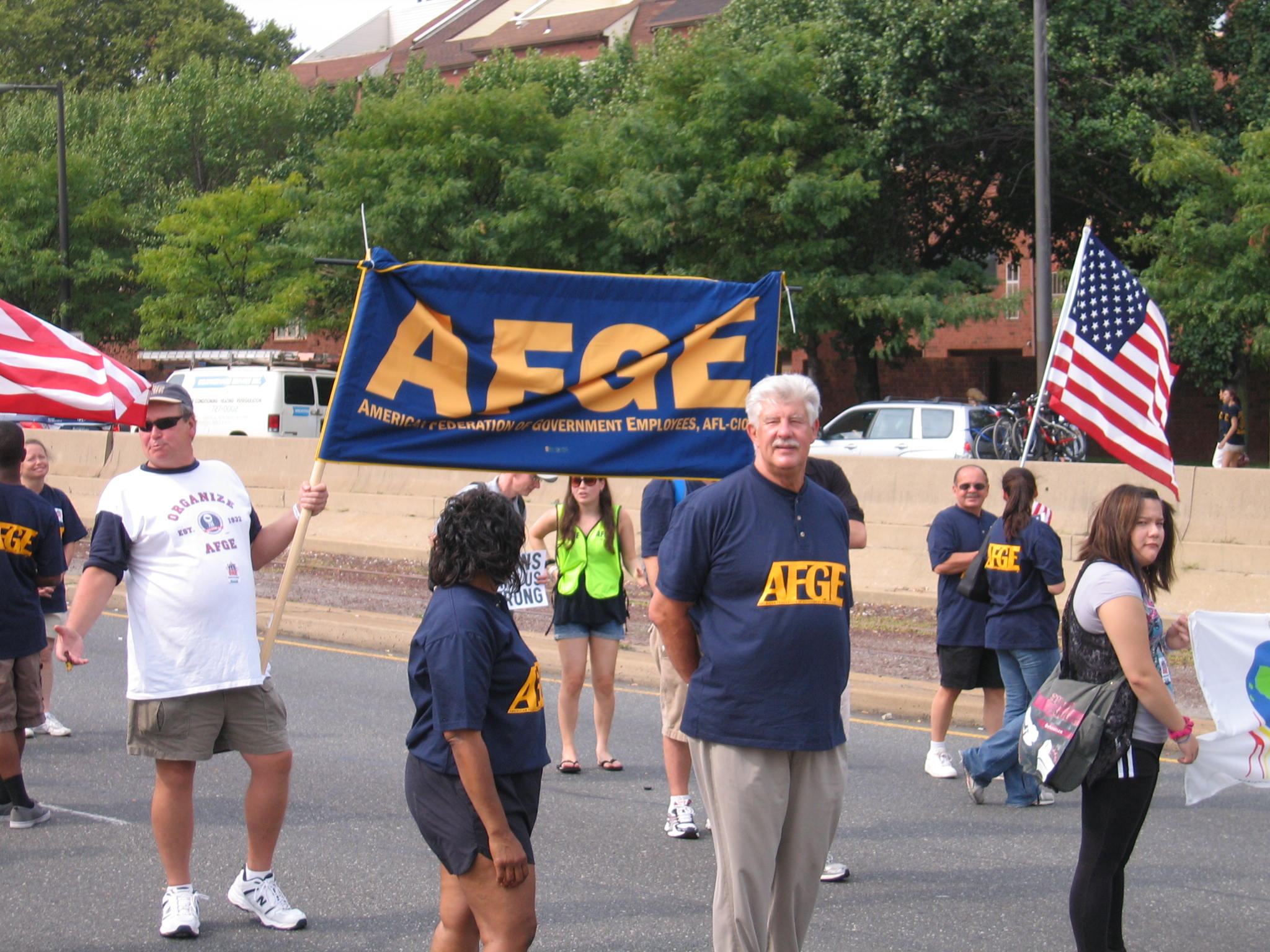 older man holding sign that says, atcg