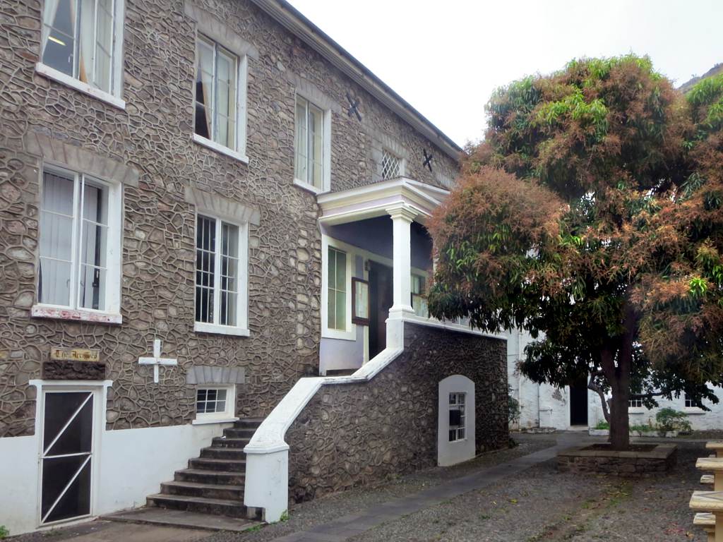 a white building with a staircase and green tree