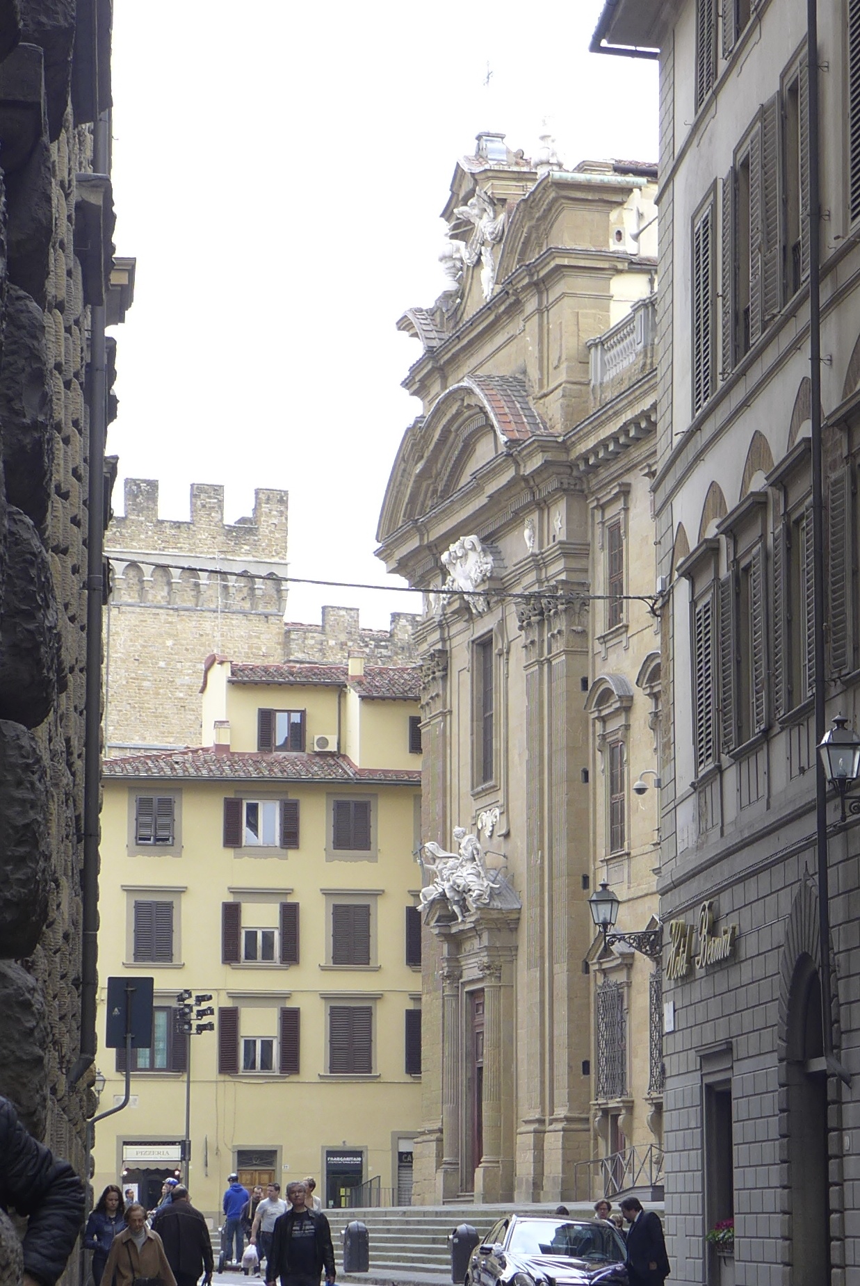 people walk down an empty city street past old buildings