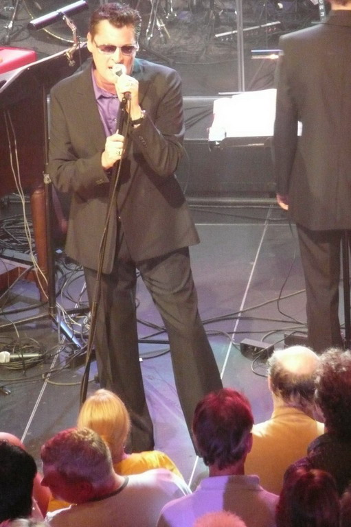 a male in a black suit singing into microphone