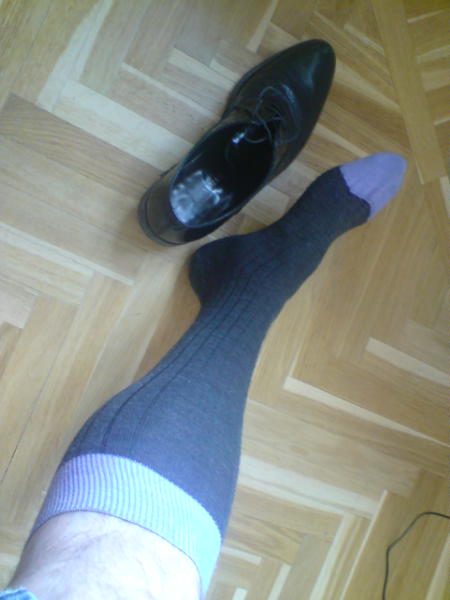 a person wearing black shoes and socks with their legs crossed