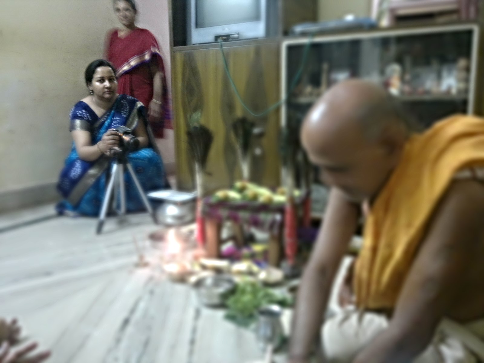 two women and a man in indian clothing standing behind candles