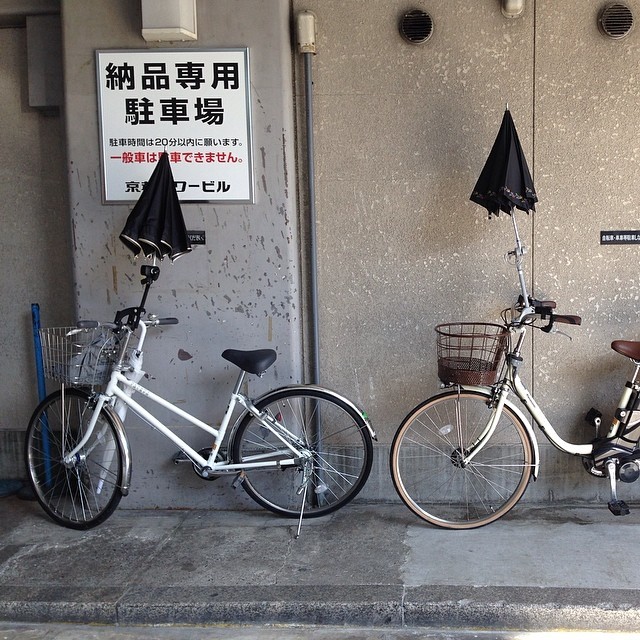 two bikes are propped up against the wall with umbrellas