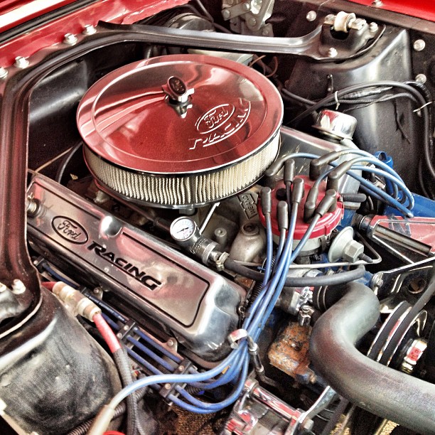 the engine of a red, classic car with no hood