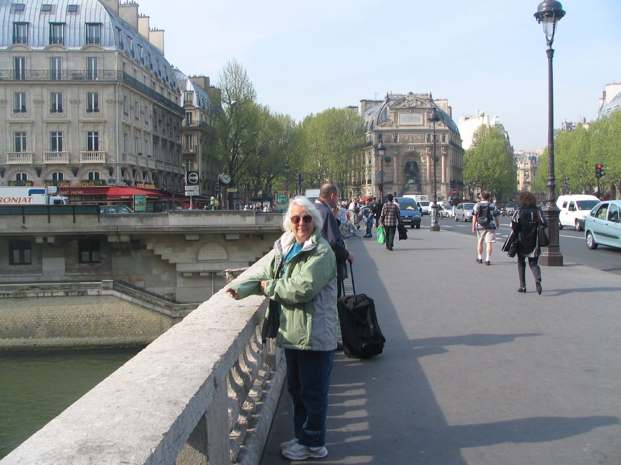 woman walking along bridge in large city next to traffic