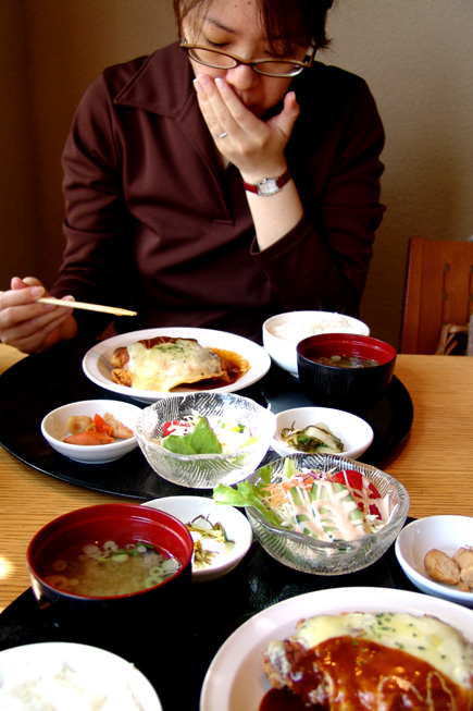 a woman eating at a restaurant with bowls of food