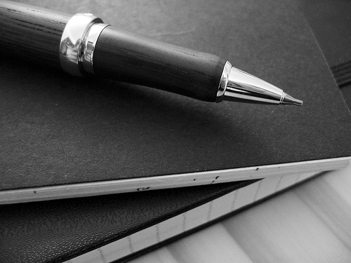 a black and white po of a pen and notepad