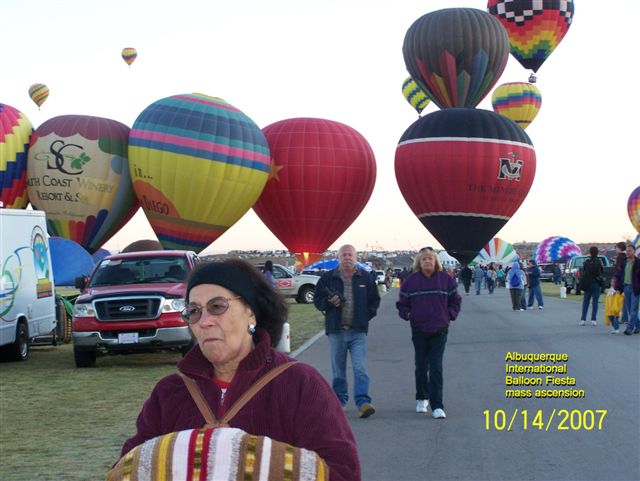 people walk by parked  air balloons at a balloon festival