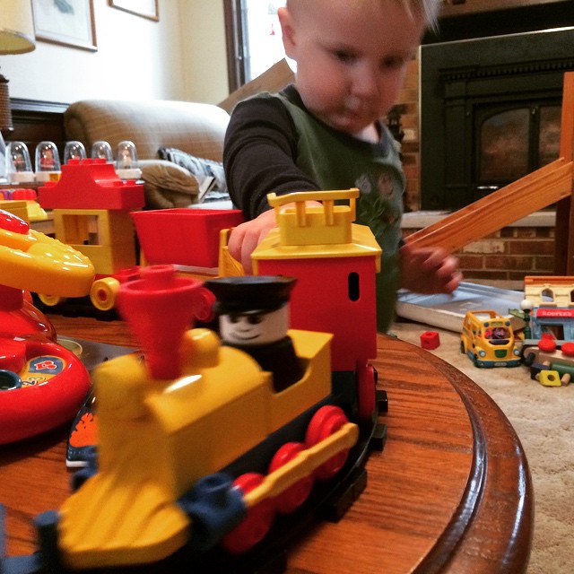 a little  with a fire engine toy next to a small train