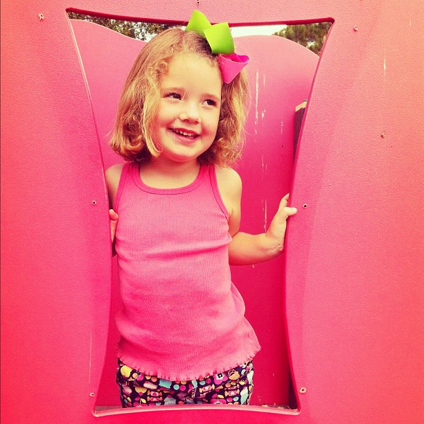 a  posing in a pink playground slide