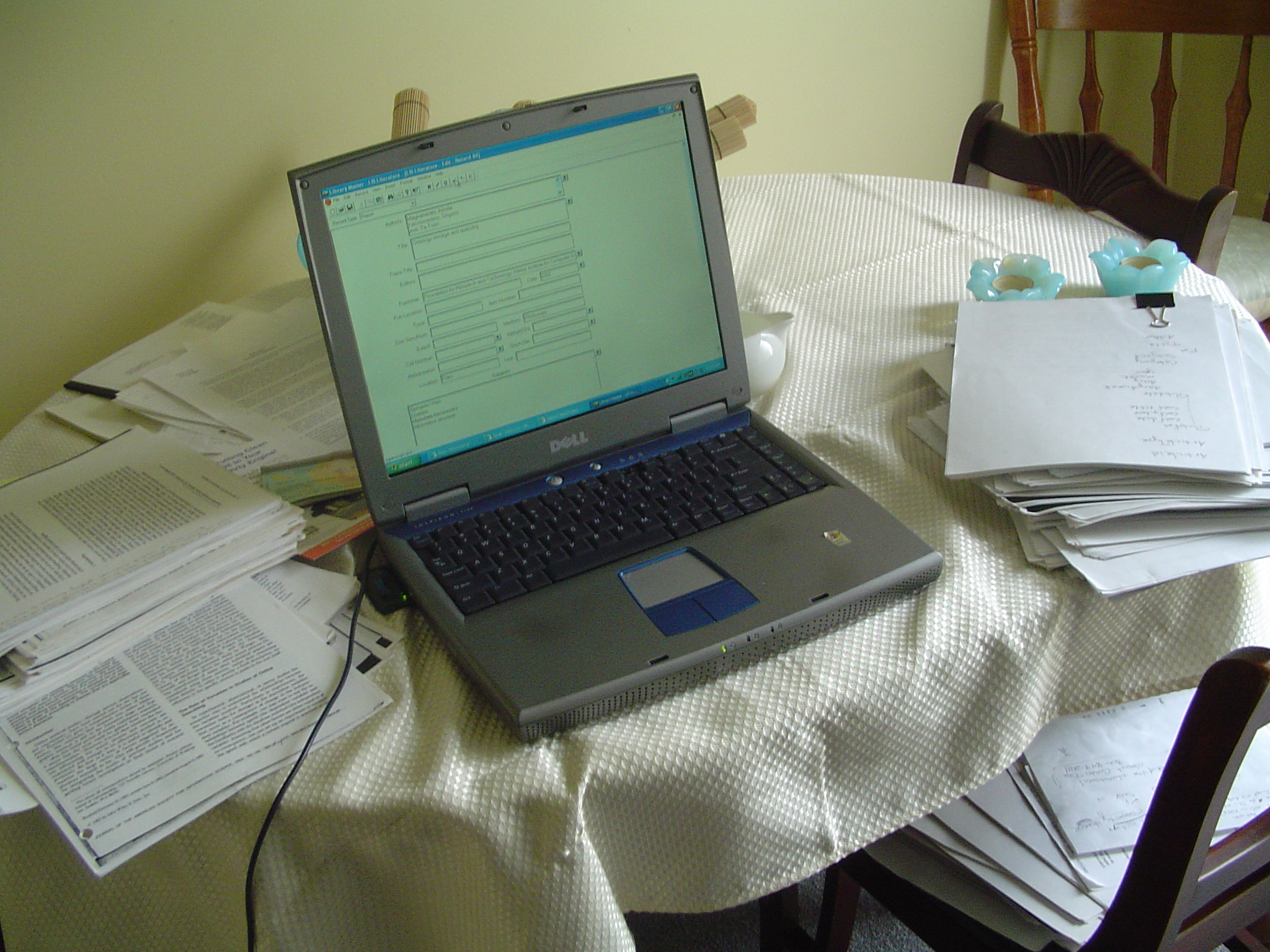 a laptop is on a table that contains books and papers