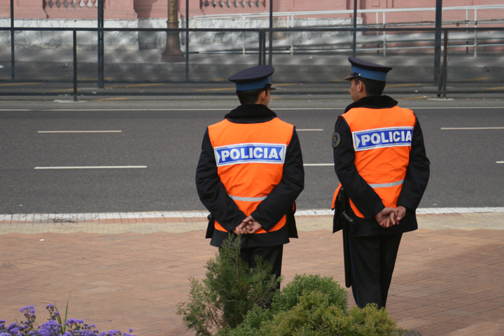 two officers in bright orange vests standing by a road