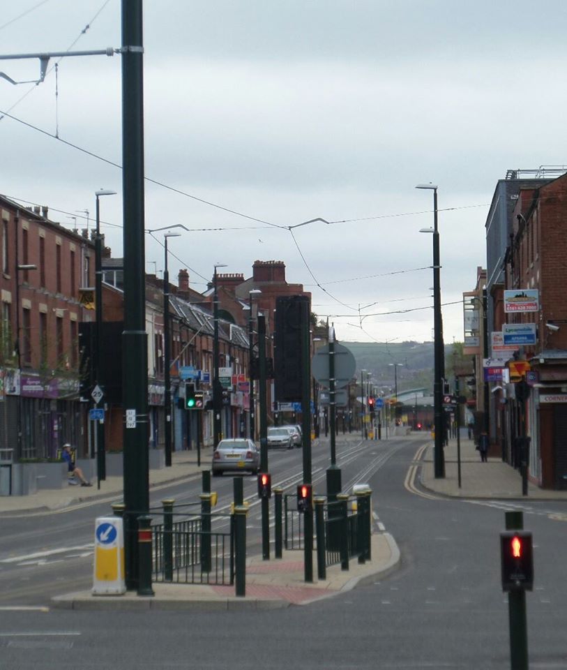 a small street with tall buildings, cars and traffic lights