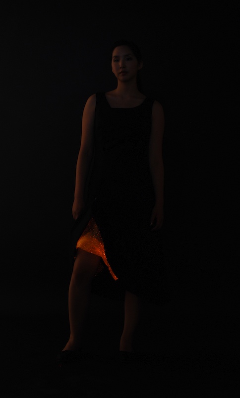a woman wearing black with a glowing orange dress