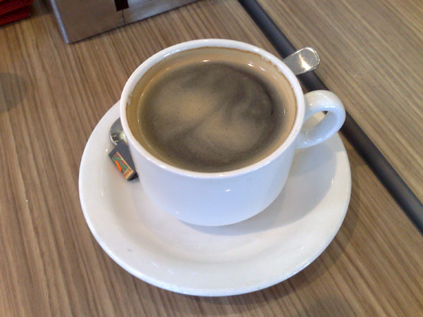 a cup of coffee sits on a saucer with spoons