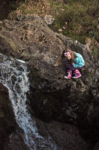 a person on top of a rock with a water stream running next to them