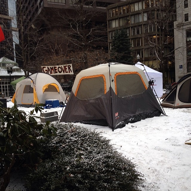 a couple of tents are in the snow by a parking lot