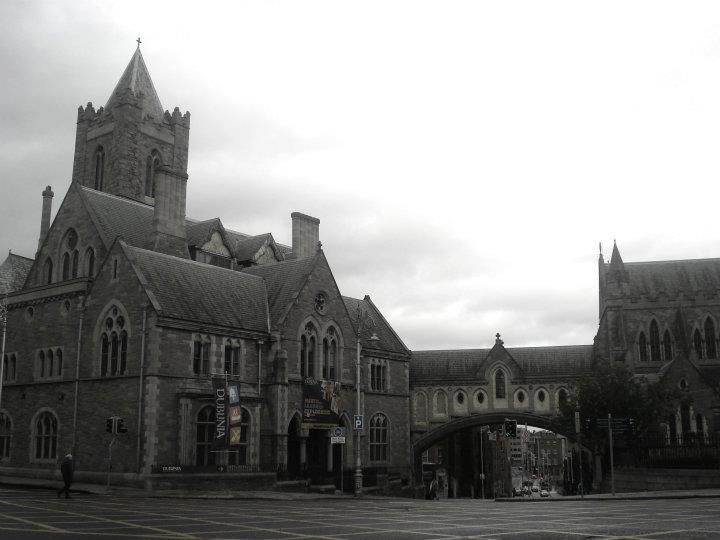 an old looking building with tall steeples under cloudy skies