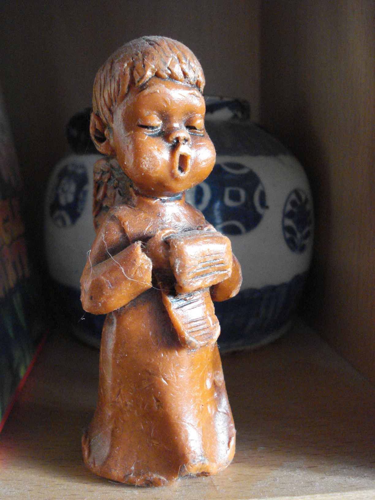a small statue of a child holding a book next to a vase